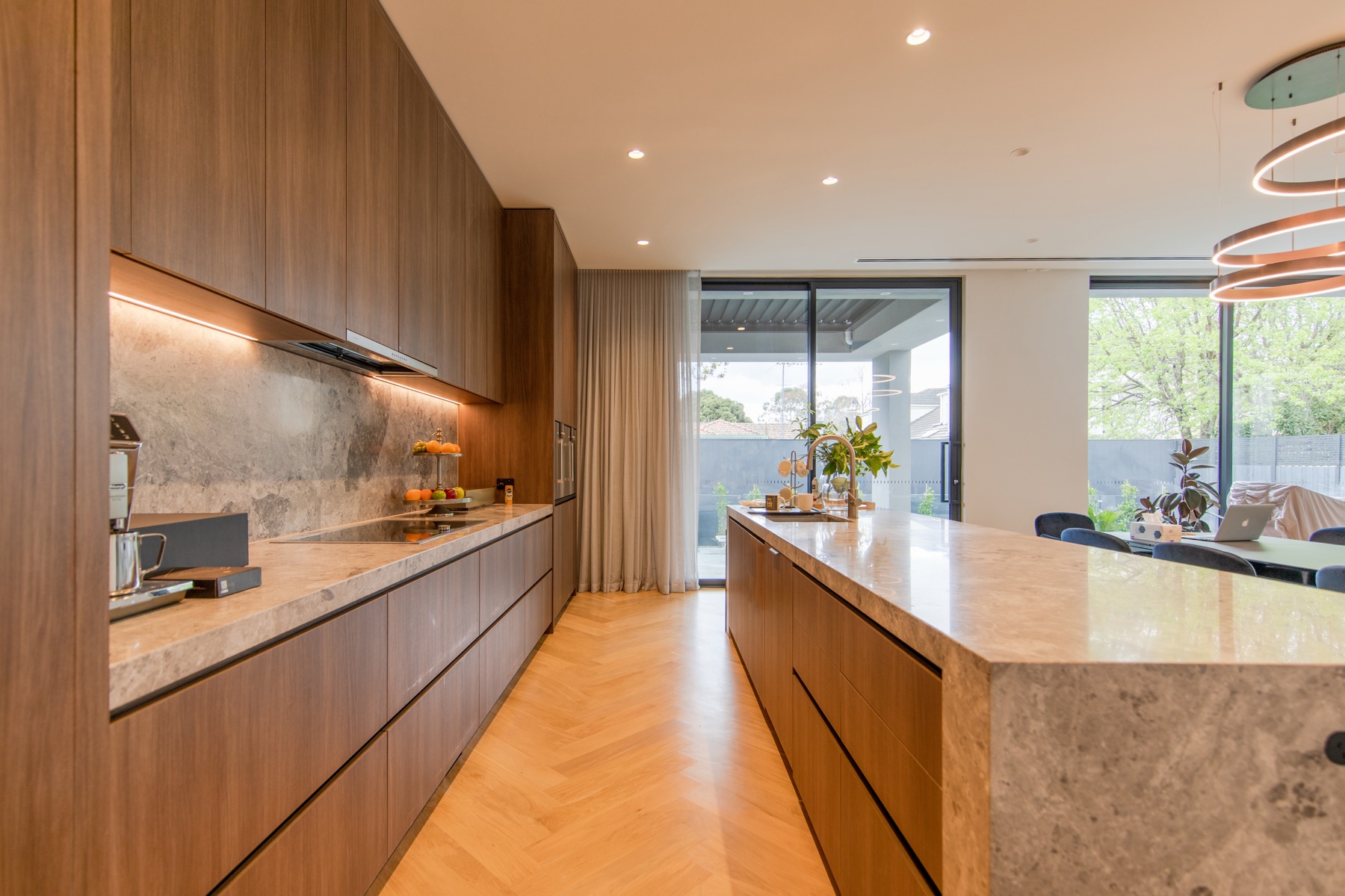 Completed HiCabinet kitchen with warm brown cabinetry, open to the living area